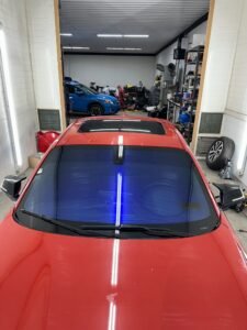 Close-up window tint installation on red car door — Garage 717